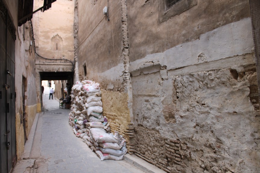 stacked sacks lined against crumbling wall