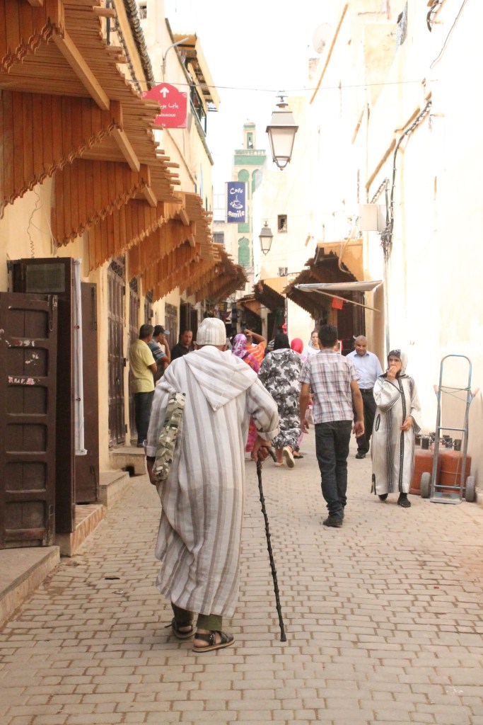 elderly man in robe with cushion and cane