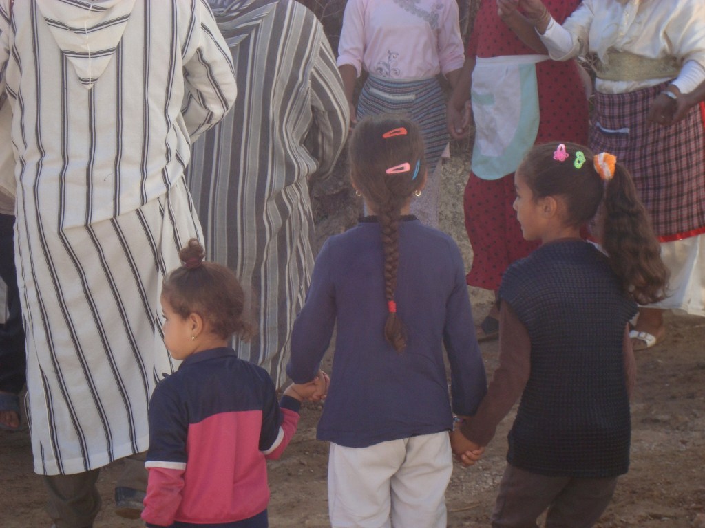 little girls holding hands next to adults in robes