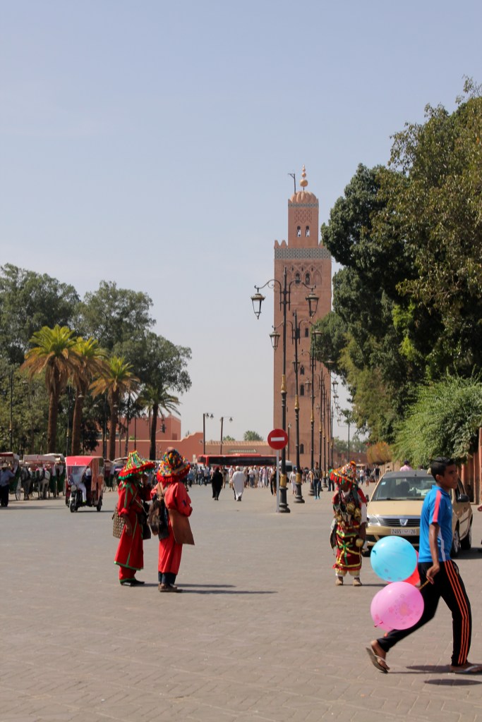 boy with balloons and people in colorful costumes in front of mosque