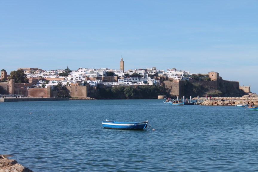 boat on blue water with city in distance