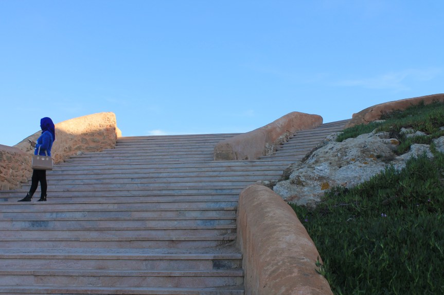 young woman on stairs leading to blue sky
