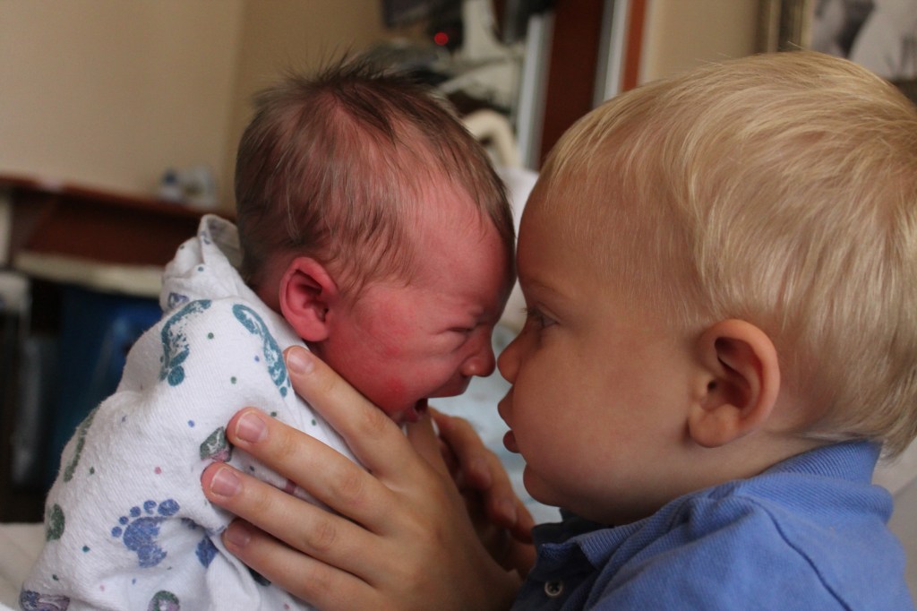 little boy nose to nose with crying baby boy