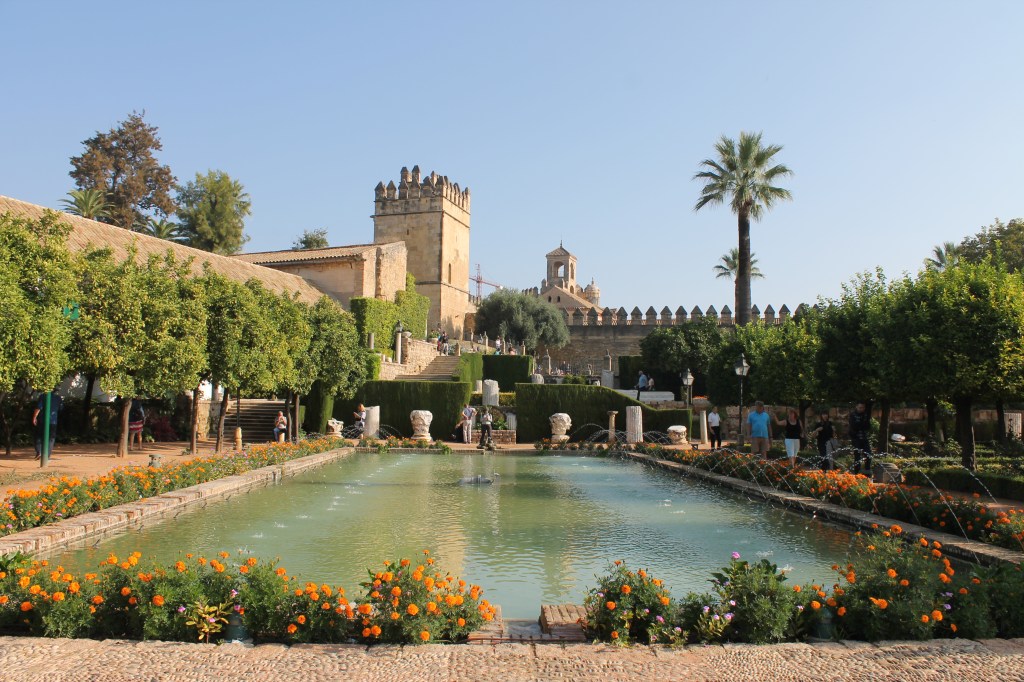pond surrounded with orange flowers with castle in background