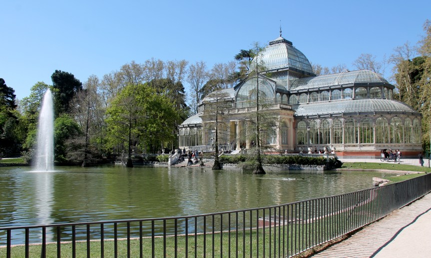 pond with fountain in front of glass building