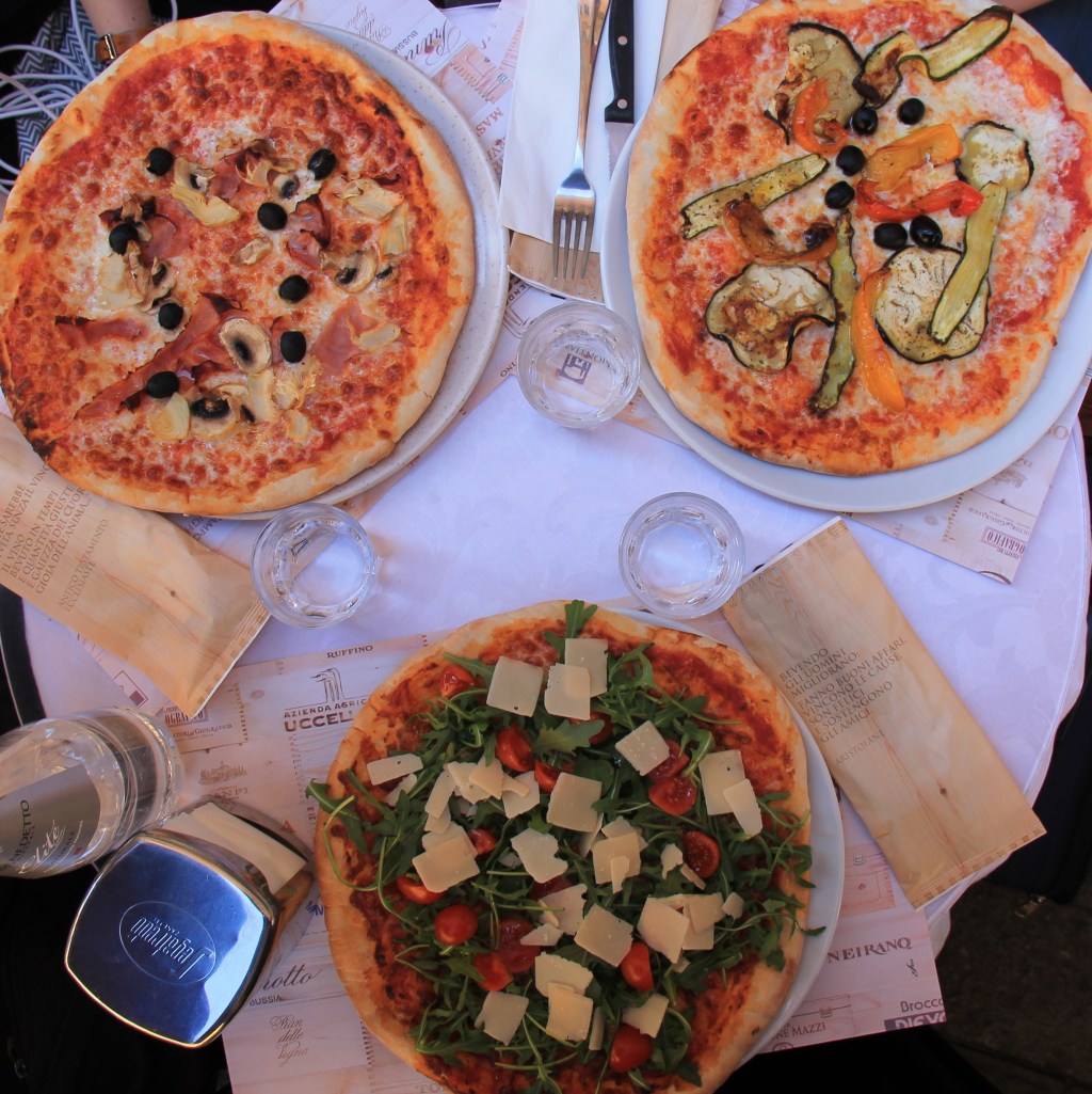 three colorful pizzas on restaurant table top