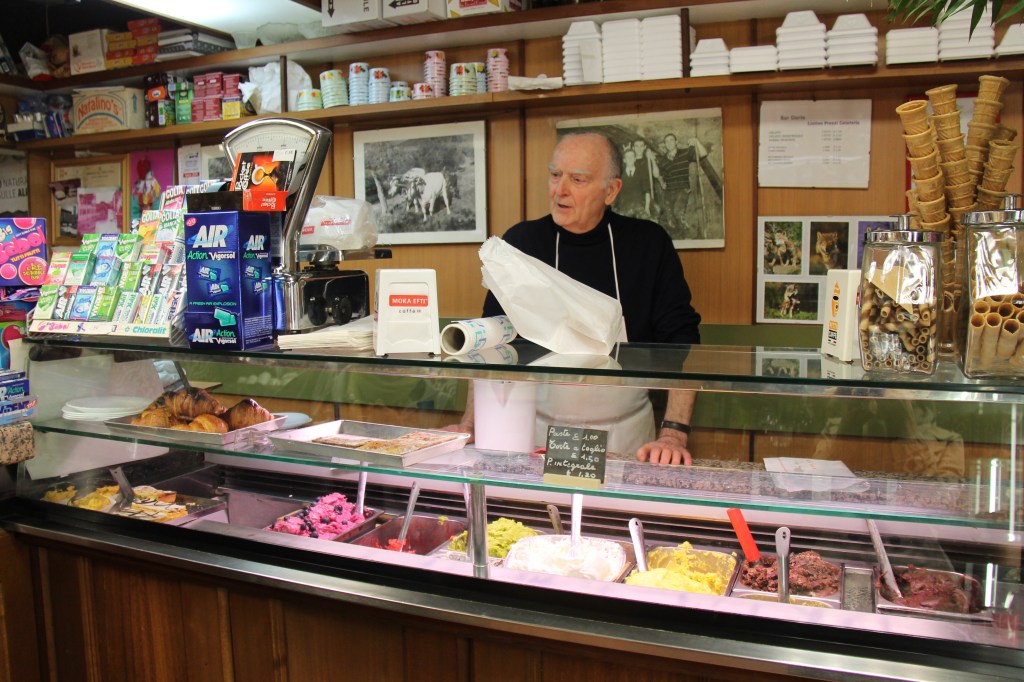 elderly man standing behind gelato counter