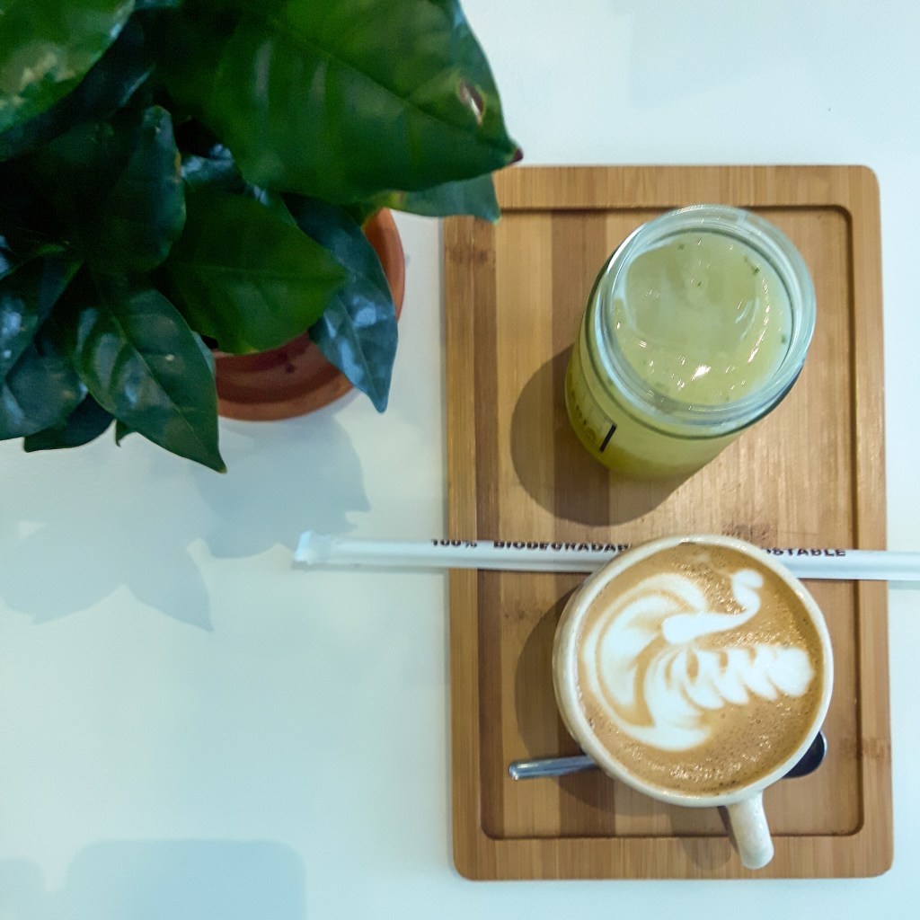 latte and smoothie on wooden tray next to plant