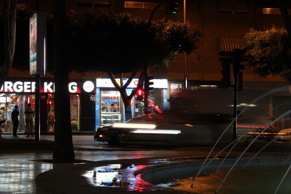 city street with blurred lights, burger king and fountain