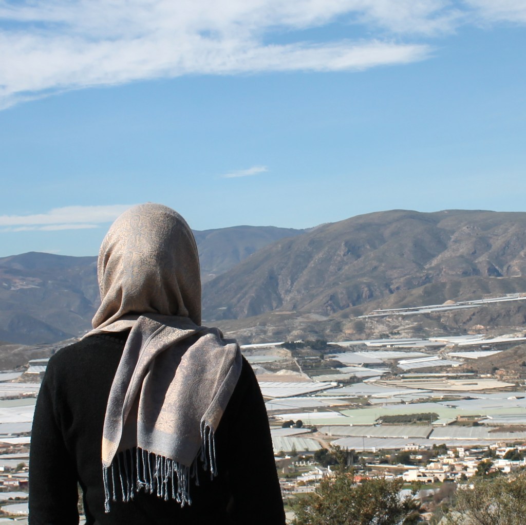 covered figure looking over greenhouses